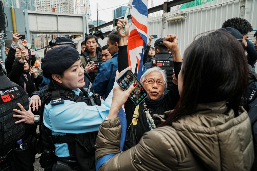 A security personnel stops a supporter who is waving the Union Jack flag outside the West Kowloon Magistrates' Courts during the national security trial of media mogul Jimmy Lai, founder of Apple Daily, in Hong Kong December 18, 2023. — Reuters pic  