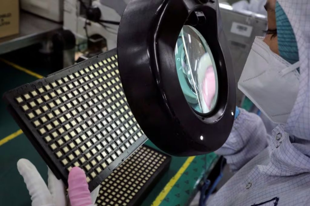 A worker inspects semiconductor chips at the chip packaging firm Unisem (M) Berhad plant in Ipoh, October 15, 2021. — Reuters pic