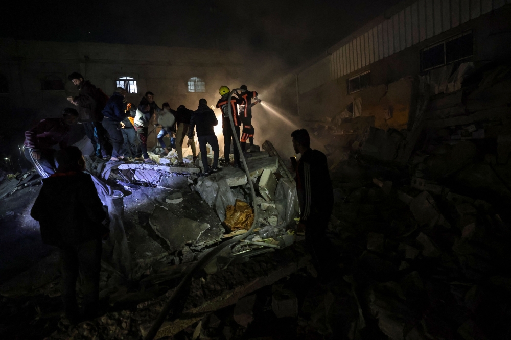 Firefighters and civilians gather at the rubble of a building following Israeli bombardment in Rafah, in the southern Gaza Strip, on December 18, 2023. ― AFP pic