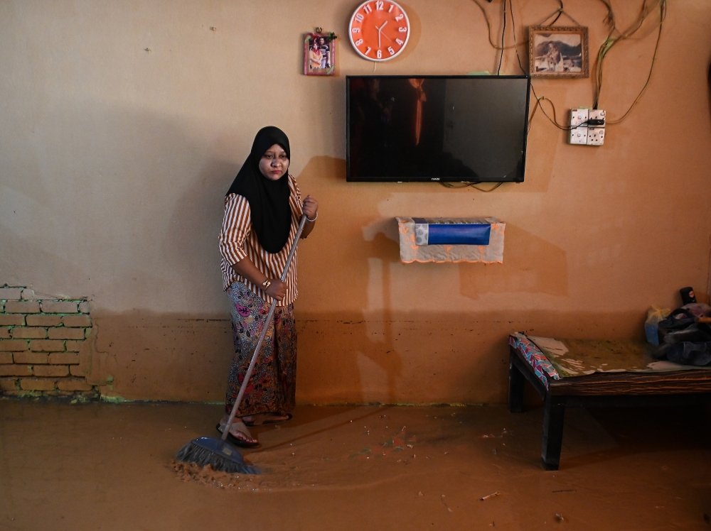 A resident cleans her mud-filled house after being hit by floods in Kampung Tok Kah, Dungun, December 17, 2023. — Bernama pic 