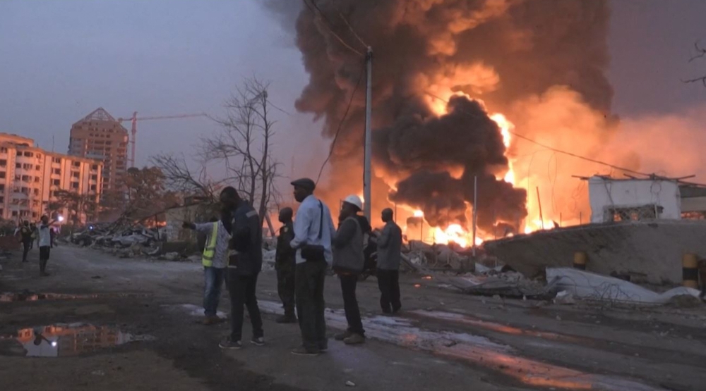 This image grab taken from AFPTV video footage on December 18, 2023 shows people in front of the flames from the fire at Conakry's main fuel depot. ― AFP pic
