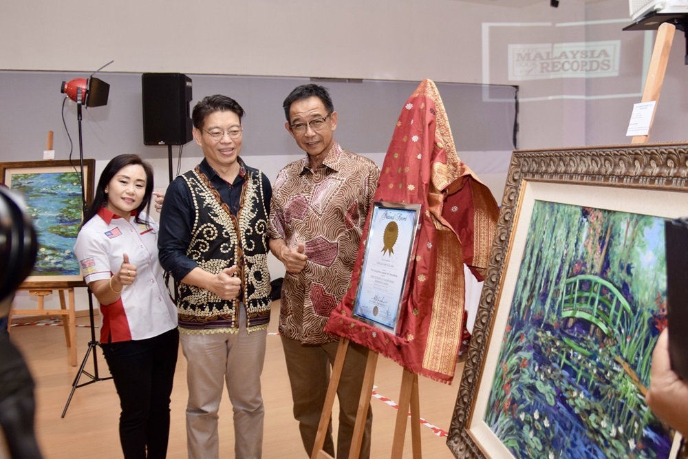 (From left) The Malaysia Book of Records office manager Lee Pooi Leng, Goh, and Abdul Karim pose with Goh’s record. Also seen are Goh’s paintings at Monet’s residence.  — Borneo Post Online pic