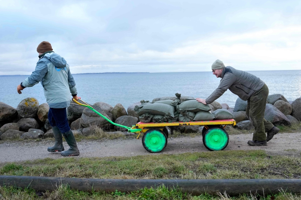Inhabitants help fill and transport sandbags to secure the harbor against the storm Pia in Niva, north of Copenhagen, Denmark, on December 20, 2023. — AFP pic