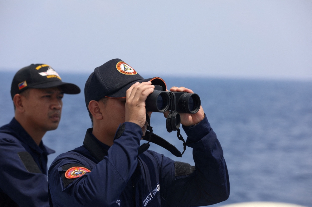 A Philippine Coast Guard personnel looks through a binocular while conducting a resupply mission for Filipino troops stationed at a grounded warship in the South China Sea, October 4, 2023. ― Reuters file pic