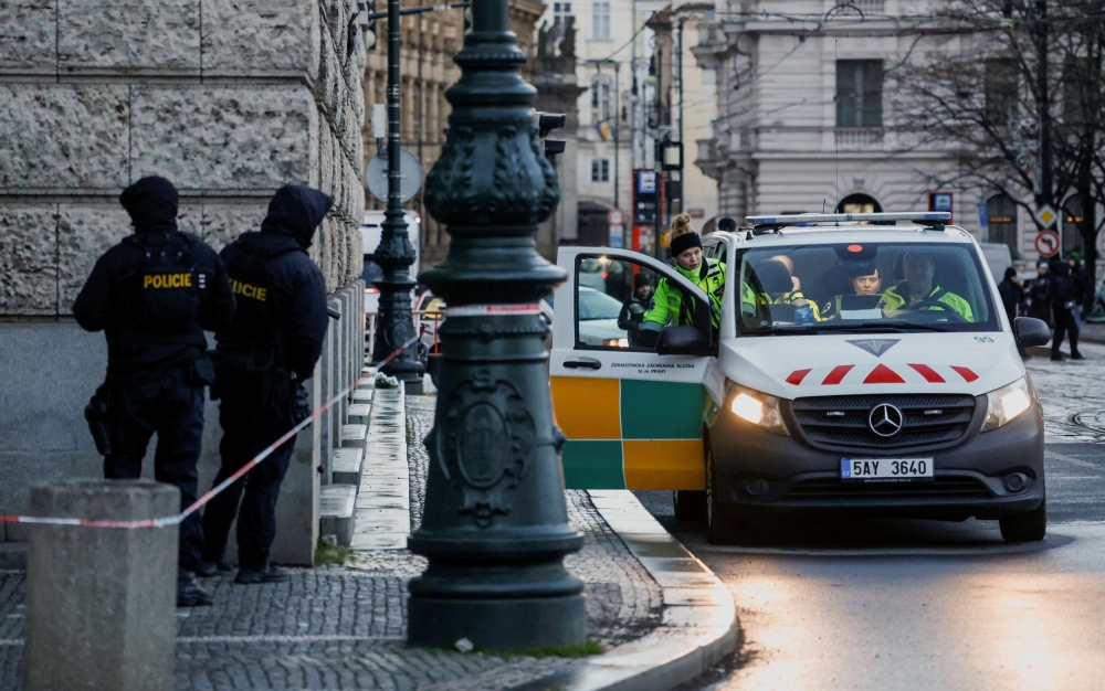 Members of the police stand guard as a policewoman gets into a police car following a shooting at one of Charles University's buildings in Prague December 22, 2023. — Reuters pic  