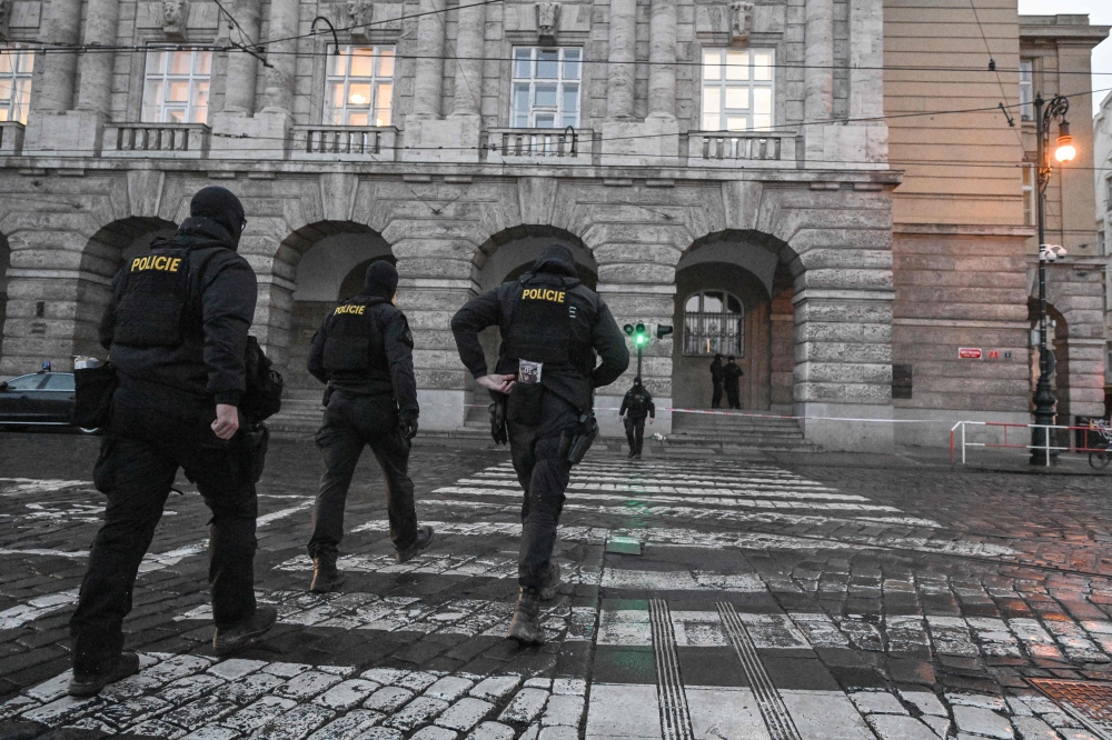 Police officers are seen in and around the Charles University in central Prague, on December 22, 2023, as police investigators kept working on the campus the day after a deadly mass shooting. — AFP pic