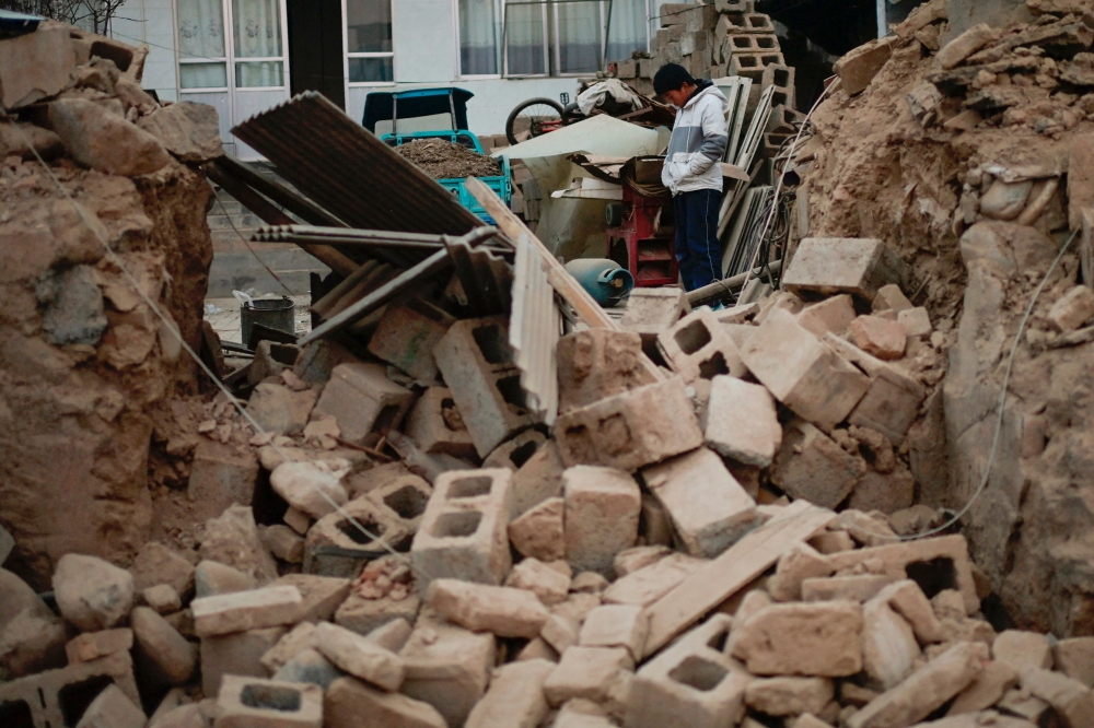 A boy stands amongst the rubble of his collapsed house in Dahejia in Jishishan County in northwest China's Gansu province December 20, 2023. — AFP pic