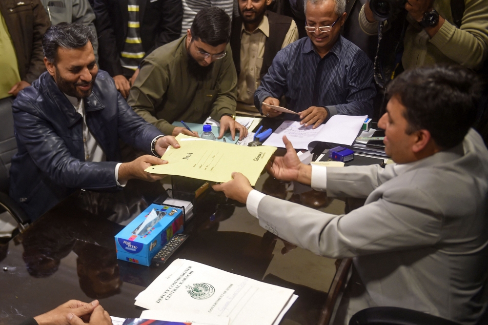 Syed Mustafa Kamal (left), Senior Deputy Convener of Muttahida Qaumi Movement-Pakistan (MQM-P) party submits nomination papers at the deputy commissioner office in Karachi December 22, 2023, ahead of the upcoming 2024 general elections. ― AFP pic