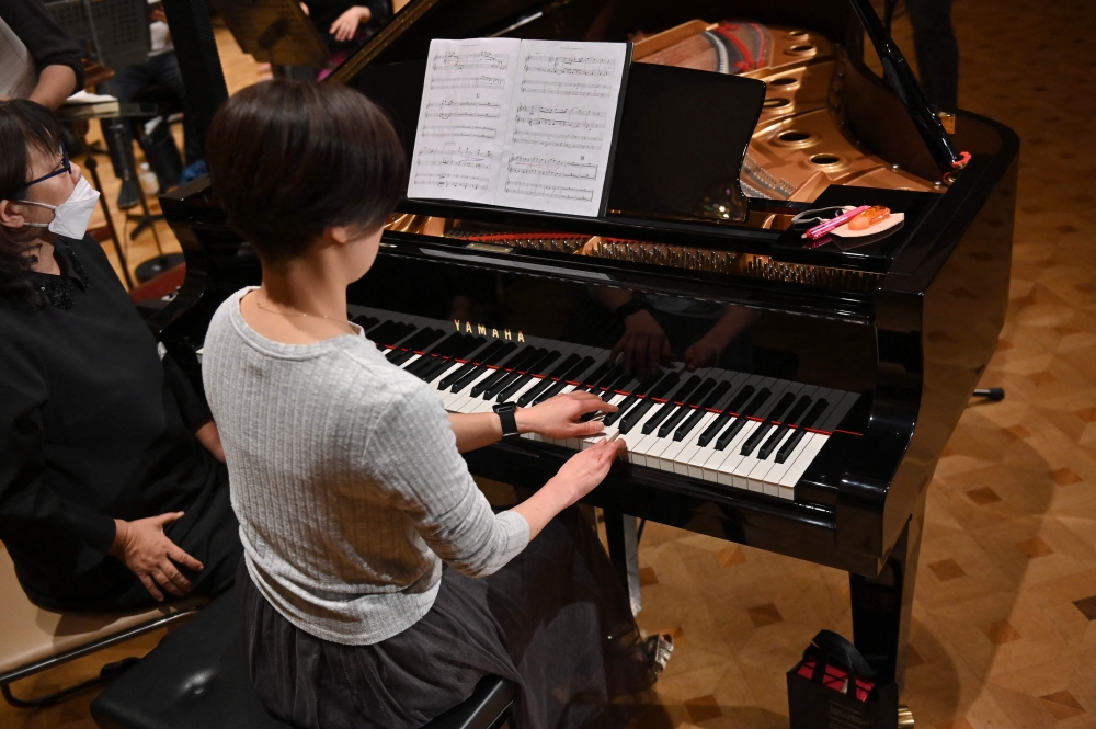 This picture taken on December 20, 2023 shows Hiroko Higashino (centre), who was born with three fingers on her right hand, playing an AI-powered piano during a Christmas concert rehearsal of Beethoven’s Symphony No 9 with the Yokohama Sinfonietta orchestra in Tokyo. ― AFP pic
