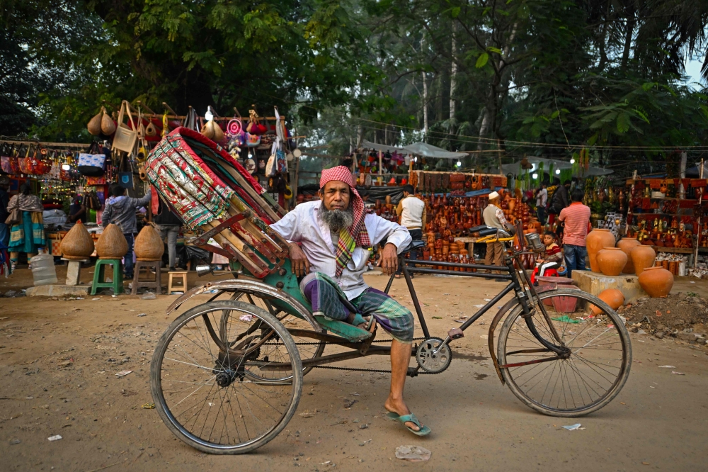 This photograph taken on December 14, 2023 shows bicycle rickshaw driver Mohammad Chan Mia posing for a portrait with his vehicle in Dhaka. — AFP pic