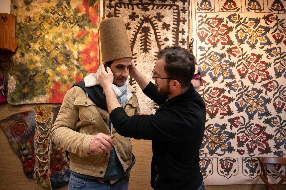 Yunus Girgic adjusts as he delivers a symbolic hat 'Sikke', worn by whirling dervishes, to his customer Ashmi Benmehidi. — AFP pic