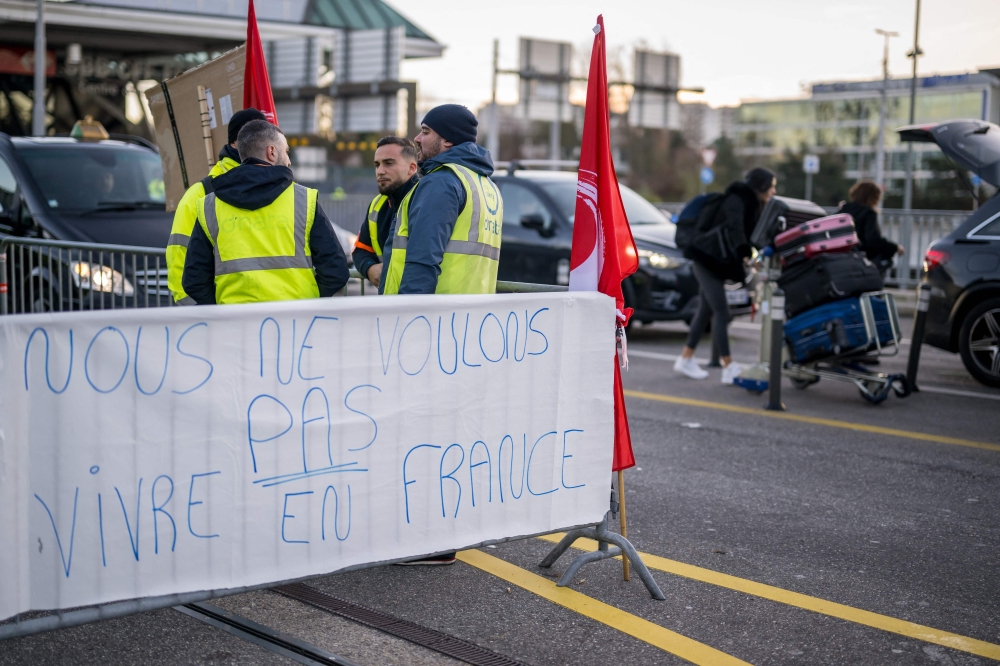 This photograph taken on December 24, 2023, shows a banner reading ‘We don’t want live in France’ during a picket line outside Geneva International Airport, after dozens of ground staff went on strike over a wage dispute with their employer, the Dubai National Air Travel Agency (DNATA) delaying flights during the busy holiday season, in Geneva. — AFP pic