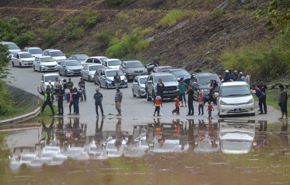 People are seen outside their vehicles after being stranded by rising floodwaters at Jalan Lojing-Pos Blau-Kuala Betis after heavy rains in Gua Musang December 24, 2023. — Bernama pic 