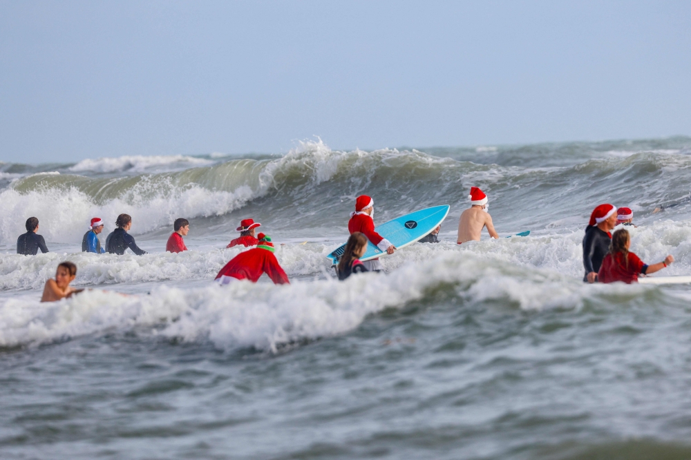 Santas of all stripes descended on Florida’s Cocoa Beach this Christmas Eve — not to deliver presents, but to ride some waves and raise funds for a good cause. — AFP pic