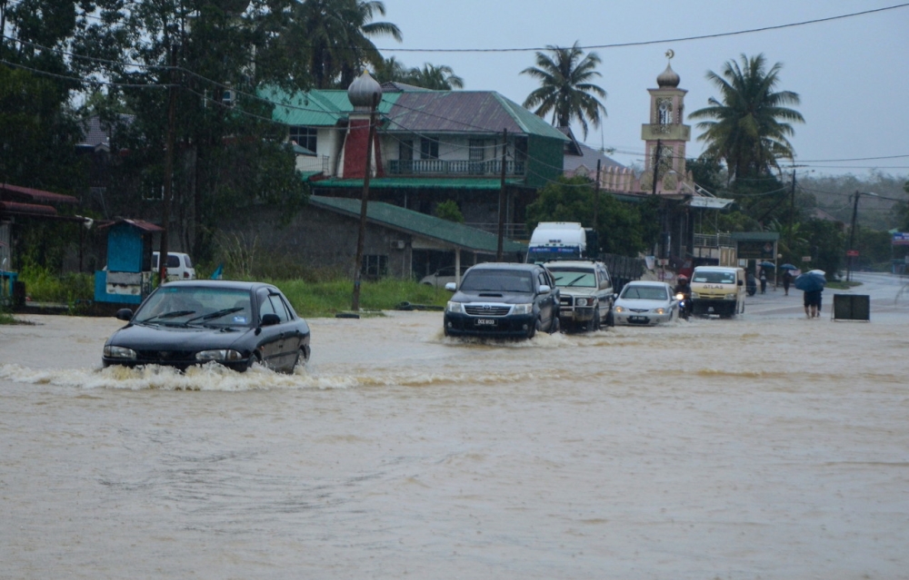 Cars passing through floodwater that overflowed Jalan Jedok-Jeli following heavy rain in Kampung Kelewek December 24, 2023. — Bernama pic