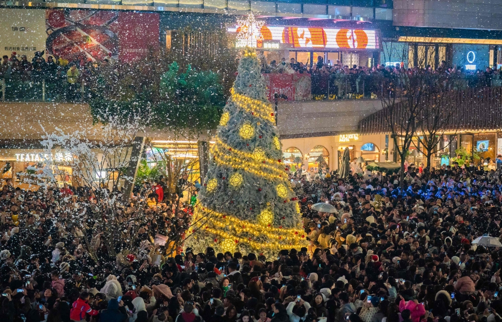 This photo taken on December 24, 2023 shows people gathering around a Christmas tree at a business area with artificial snow in China's southwestern Chongqing municipality. — AFP pic
