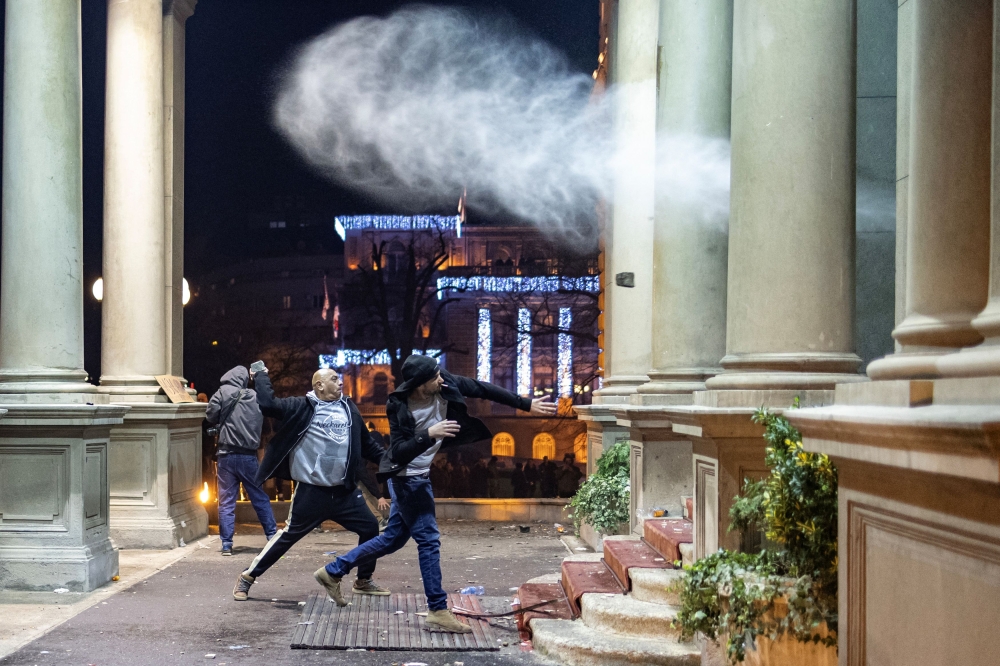 Protesters throw rocks to police officers that guard the door of the city hall during a protest by supporters of the opposition 'Serbia Against Violence' (SPN), after the SPN alleged major election law violations in the Belgrade city and parliament races, in Belgrade, Serbia, December 24, 2023. — Reuters pic