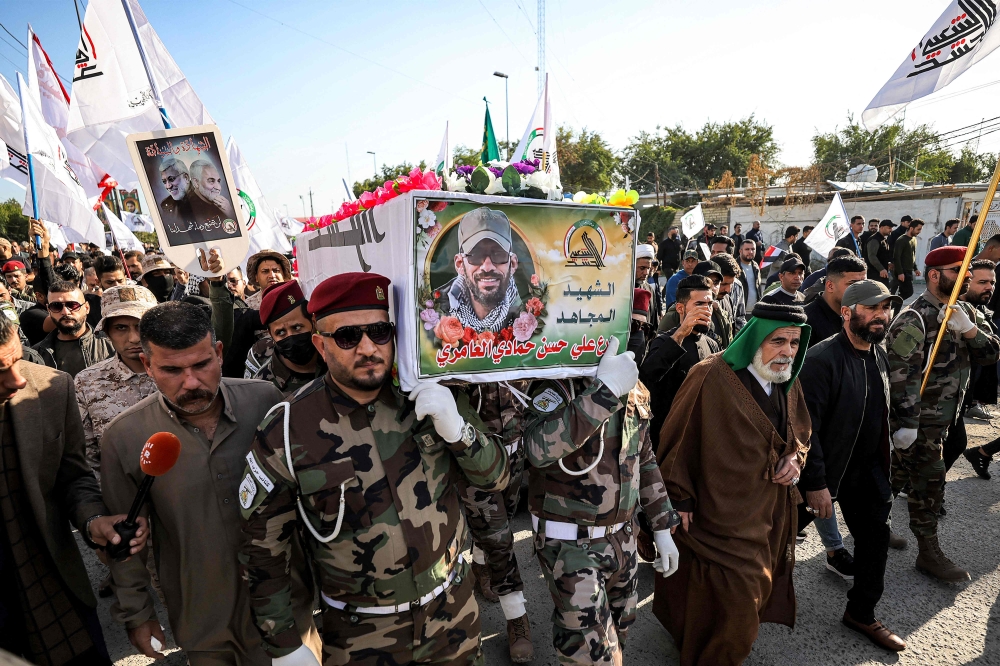 Members of the group Kataeb Hezbollah, one of the factions of Iraq's Hashed al-Shaabi (Popular Mobilisation Forces - PMF) paramilitaries, carry the body of their fallen comrade Hassan Hammadi al-Amiri during his funeral in Baghdad on December 26, 2023, after he was killed earlier in a US airstrike. — AFP pic
