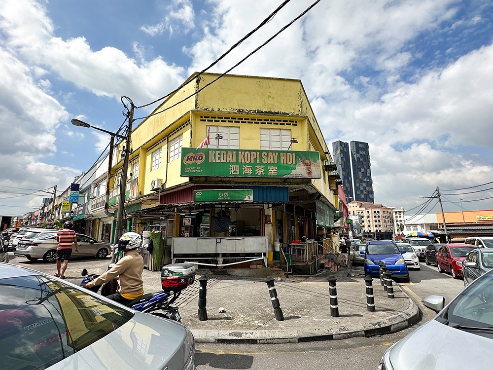 The coffee shop is right opposite the wet market in this popular area that is often jam packed with cars .