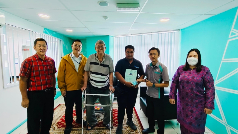 Norazizan (second right) hands over the blue IC to Jin Hong, witnessed by his father, Hua Chiaw, Lau and others. — Borneo Post Online pic
