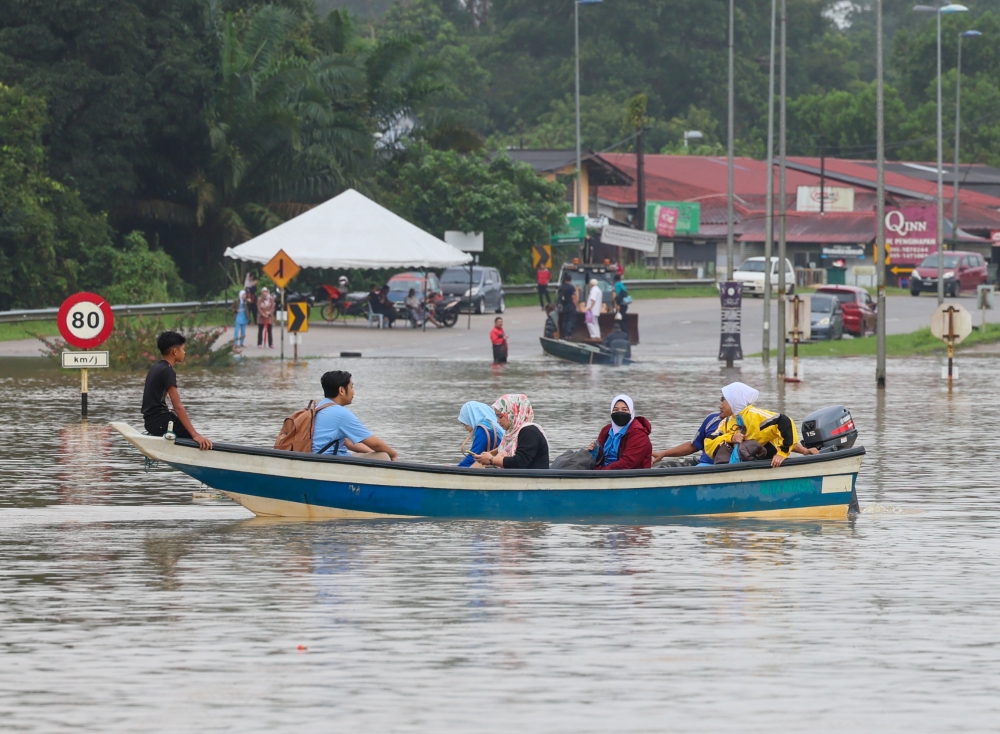 Hulu Terengganu Hospital staff board a boat to go to the hospital after the main Ajil-Kuala Berang road was cut off due to flooding in Kuala Berang, Terengganu, December 27, 2023. — Bernama pic 