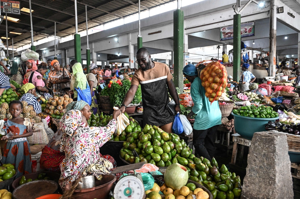 Ivorian chef Charlie Koffi (centre) buys ingredients for the preparation of a gouagouassou sauce, at the Adjame market in Abidjan on December 4, 2023. — AFP pic 