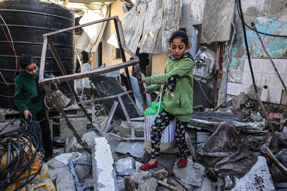 Palestinian girls search the rubble of a building following Israeli bombardment in Rafah in the southern Gaza Strip. — AFP pic