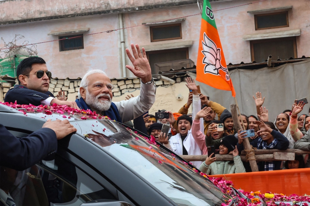 This handout photograph taken on December 30, 2023 and released by Indian Press Information Bureau (PIB) shows India’s Prime Minister Narendra Modi (second left) greeting people during a roadshow in Ayodhya. — AFP pic