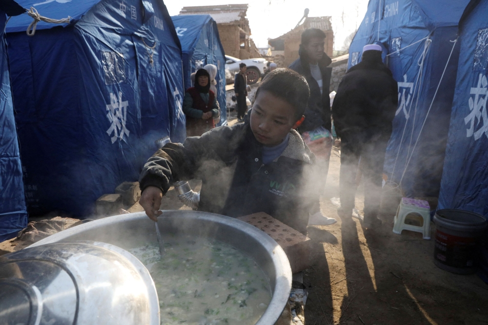 A boy checks a food pot at a temporary shelter for quake-affected victims at Yangwa village following the earthquake in Jishishan county, Gansu province, China. — Reuters pic