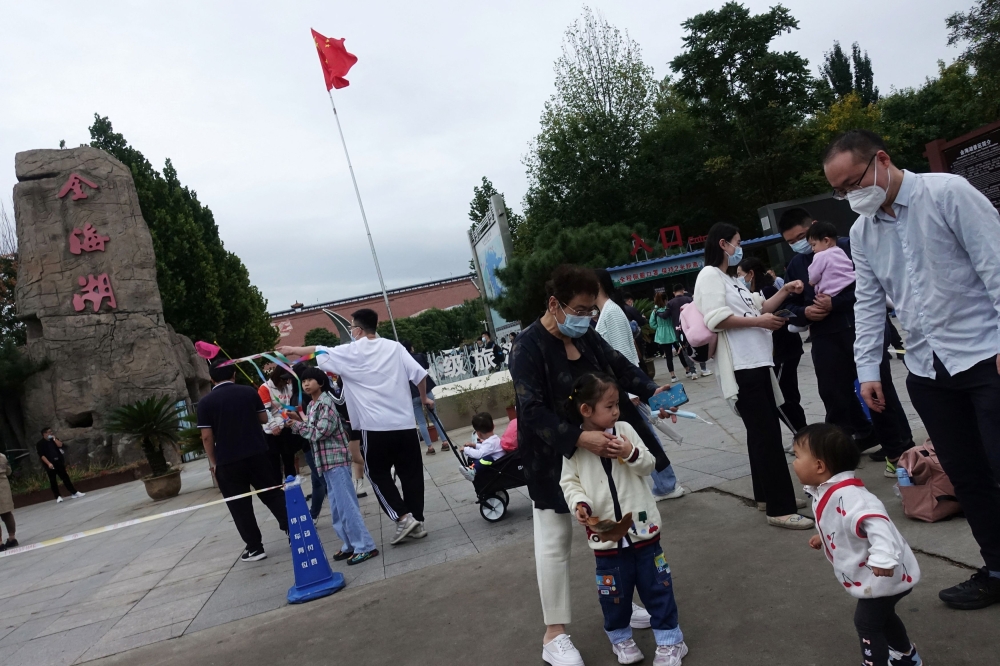 Tourists stand near a Chinese national flag at a tourist site during the National Day holiday, in the outskirts of Beijing, China October 2, 2022. ― Reuters pic
