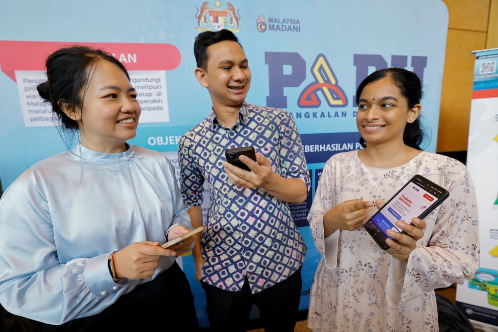 Three friends (from right) Lokita Karthyayini Supramaniam, Mohamad Amjad Mohamed Zahari and Phang Yoke Hang registered in the new Primary Database (Padu) which was inaugurated by the Prime Minister at the Putrajaya International Convention Center (PICC) today. — Bernama pic 