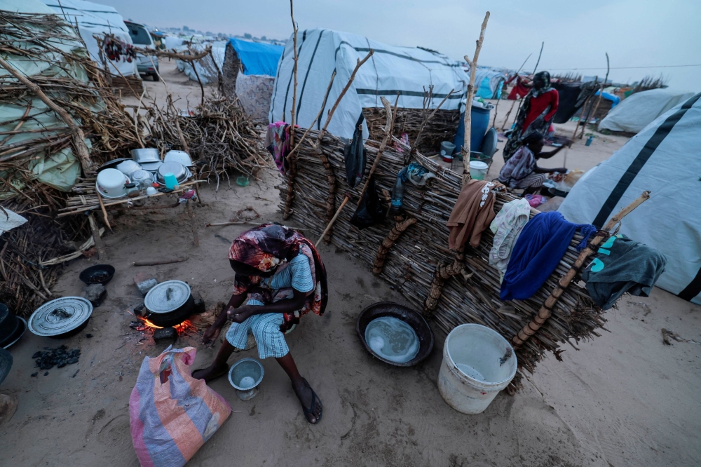  Sudanese women, who fled the conflict in Sudan's Darfur region, cook at their makeshift shelters in Adre, Chad August 3, 2023.  — Reuters pic