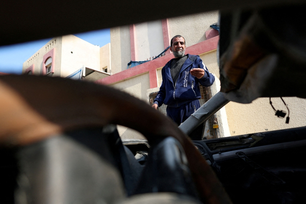 Palestinian man Hamada Abu Sleyma, whose wife, all his 6 children and two grandchildren were killed in an Israeli strike that destroyed his house, stands near his destroyed car, in Rafah in the southern Gaza Strip, January 1, 2024. — Reuters pic