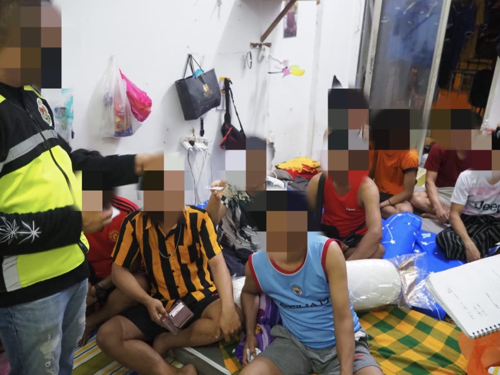 A Johor Immigration enforcement officer checking travel documents of several foreigners detained during a raid in Skudai January 3, 2024 — Picture courtesy of the Johor Immigration Department