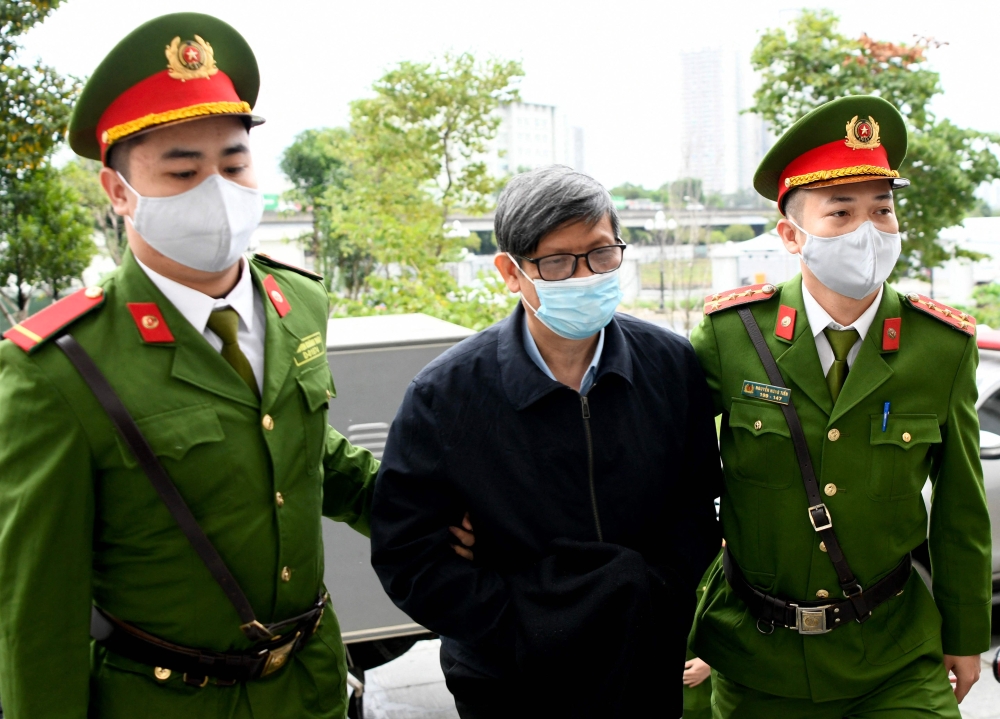 Vietnam's former minister of health Nguyen Thanh Long (centre) is led into a court by police for his anti-corruption trial over Covid test kit production bribes in Hanoi on January 3, 2024. — AFP pic
