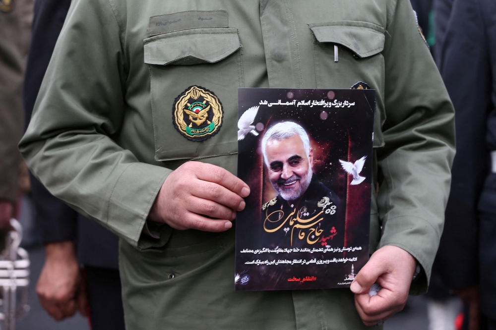 An Iranian policeman man holds a picture of late General Qassem Soleimani, head of the elite Quds Force, who was killed in an air strike at Baghdad airport, as people gather to mourn him in Tehran, Iran January 4, 2020. — WANA pic via Reuters