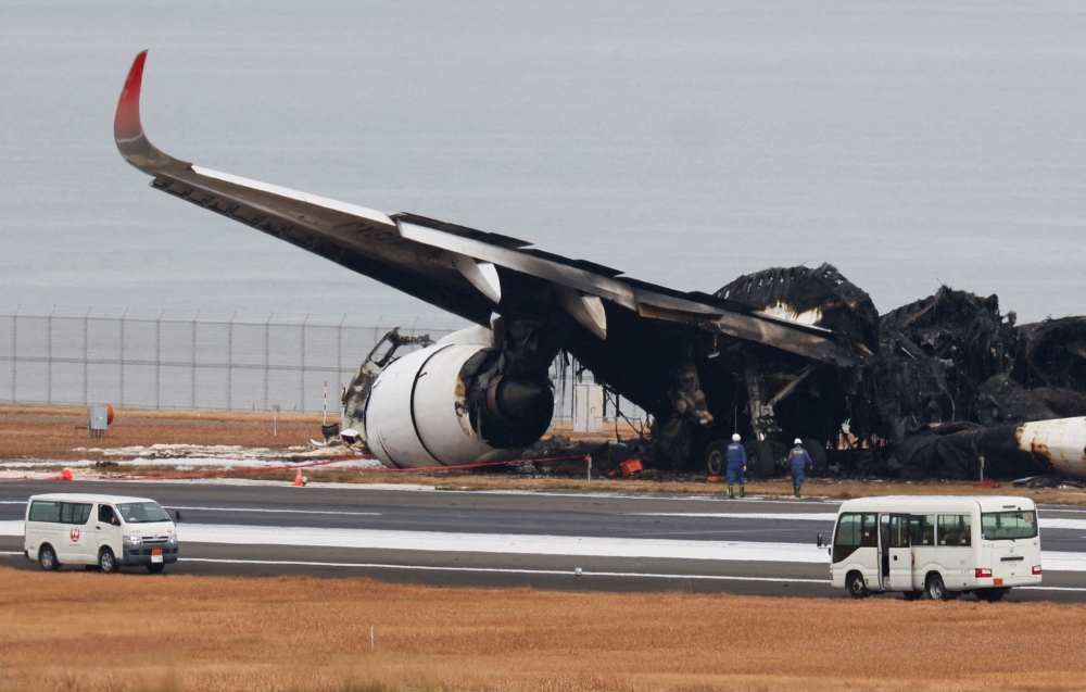 Officials investigate a burnt Japan Airlines (JAL) Airbus A350 plane after a collision with a Japan Coast Guard aircraft at Haneda International Airport in Tokyo, Japan January 3, 2024. — Reuters pic