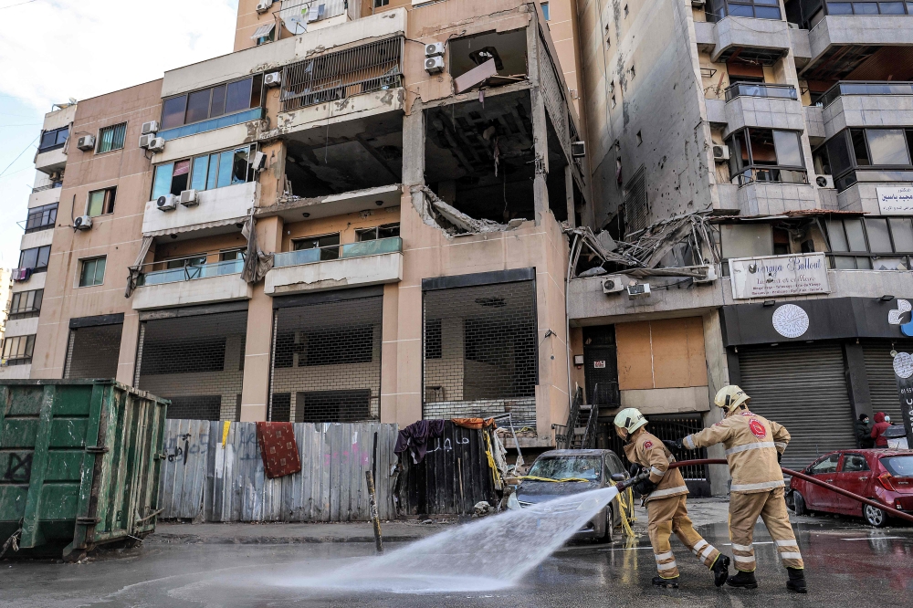  Lebanese civil defence members spray with water the street by the building that was hit by an Israeli strike targeting Hamas deputy leader Saleh al-Aruri in the southern suburb of Beirut on January 3, 2024. — AFP pic