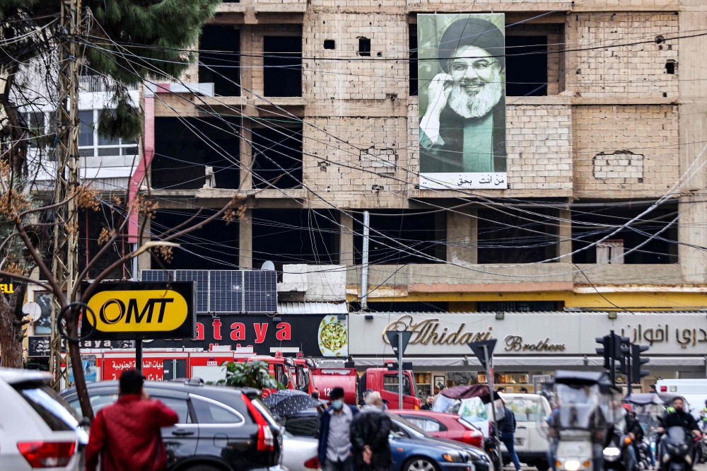 A picture depicting Hassan Nasrallah, the leader of the Lebanese Shiite movement Hezbollah, hangs on a building near the site of an Israeli strike targeting Hamas deputy leader Saleh al-Aruri in the southern suburb of Beirut on January 3, 2024. — AFP pic