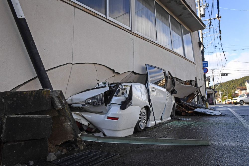 A car is seen under part of a building in Anamizu, Ishikawa prefecture on January 4, 2024, after a major 7.5 magnitude earthquake struck the Noto region in Ishikawa prefecture on New Year's Day. — AFP pic
