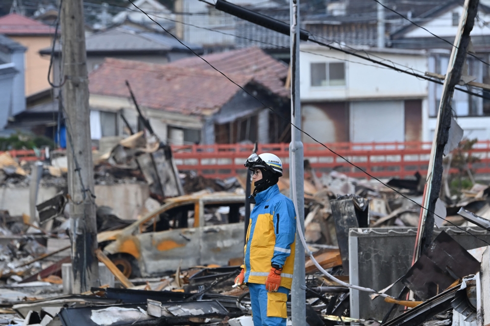 A policeman observes rescue operations at the ruins of a shopping district in the city of Wajima, Ishikawa prefecture on January 4, 2024, after a major 7.5 magnitude earthquake struck the Noto region in Ishikawa prefecture on New Year's Day. — AFP pic