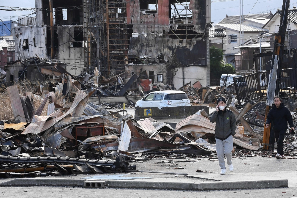 People walk past the burned Wajima Asa-ichi, or morning market area, in the city of Wajima, Ishikawa prefecture, on January 5, 2024, after a major 7.5 magnitude earthquake struck the Noto region on New Year's Day. — AFP pic