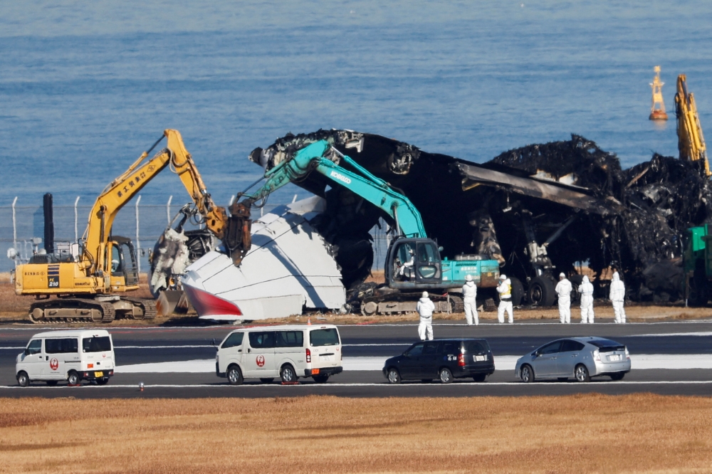 Officials try to remove the wreckage of a burnt Japan Airlines (JAL) Airbus A350 plane after a collision with a Japan Coast Guard aircraft at Haneda International Airport in Tokyo, Japan, January 5, 2024. — Reuters pic