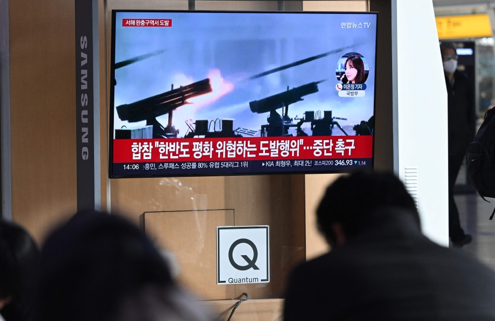 People watch a television screen showing a news broadcast with file footage of North Korea's artillery firing, at a railway station in Seoul on January 5, 2024. — AFP pic