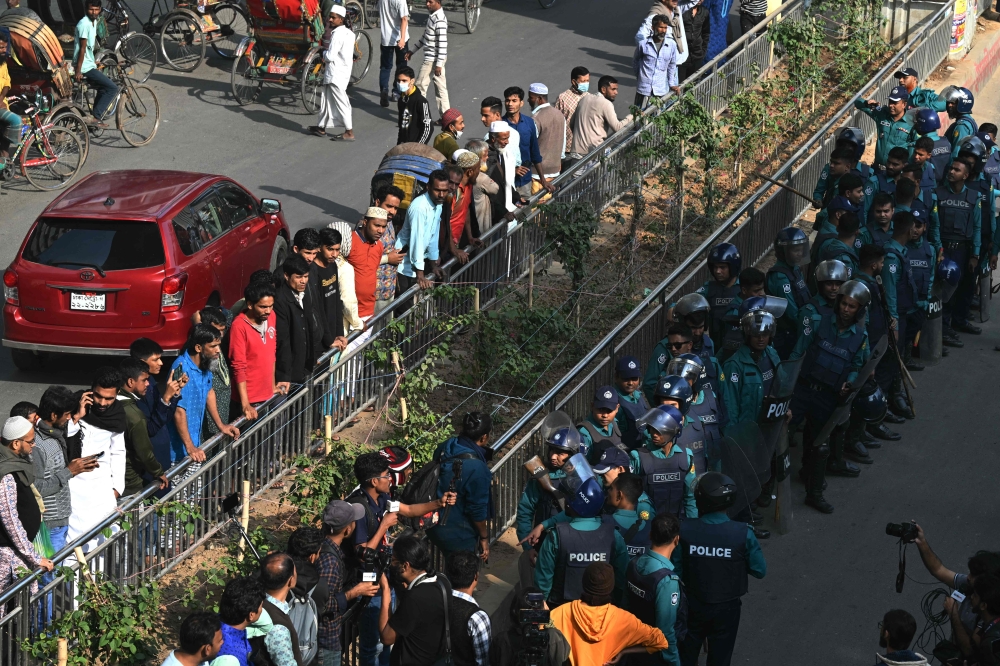 Onlookers line a street as police stand guard outside a mosque during Friday prayers, ahead of the upcoming general elections, in Dhaka January 5, 2024. — AFP pic 