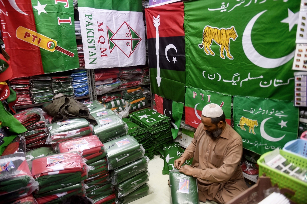 A shopkeeper arranges flags of political parties at his shop ahead of the upcoming general elections in Karachi January 3, 2024. — AFP pic 