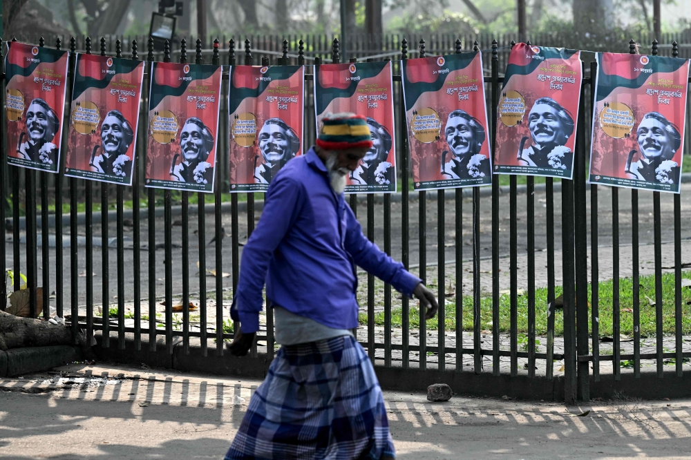 A pedestrian walks past posters of Bangladesh's founding father Sheikh Mujibur Rahman, ahead of the upcoming general elections, in Dhaka on January 5, 2024. — AFP pic 
