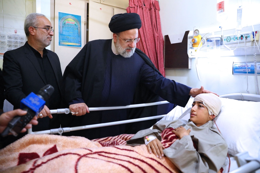 A handout picture provided by the Iranian presidency on January 5, 2024, shows Iran’s President Ebrahim Raisi (right) at the bedside of a person injured in January 3 twin blasts in Kerman, at a hospital in the southern city. ― AFP pic