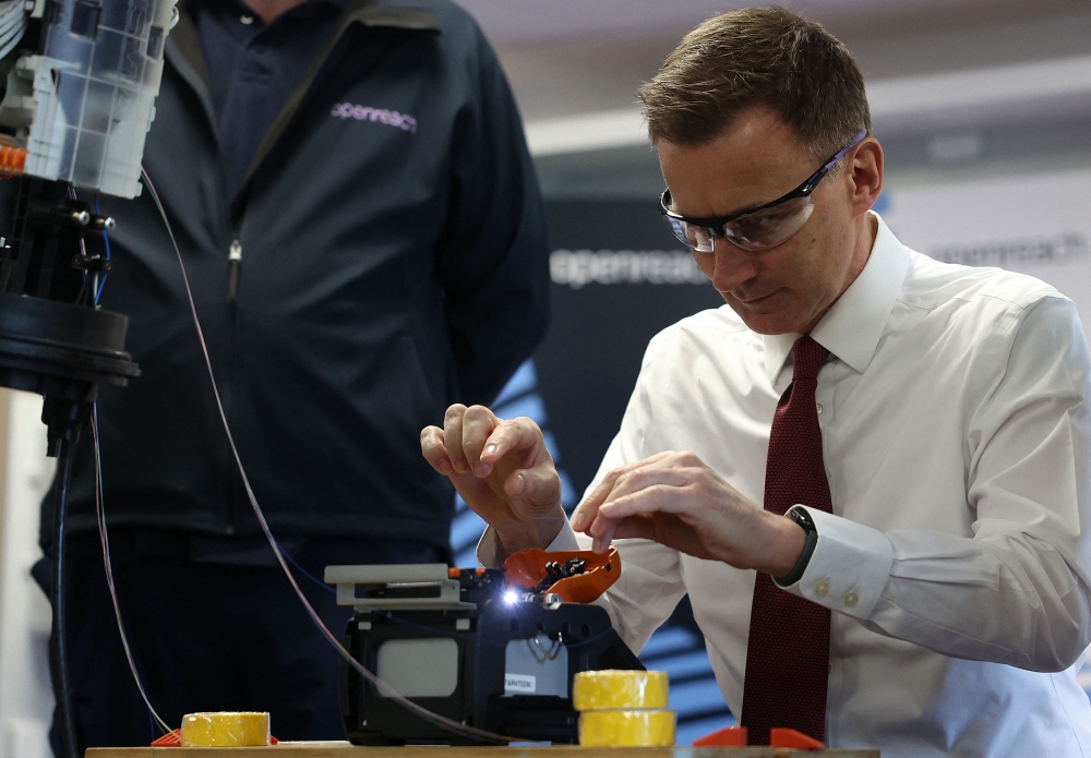 Britain's Chancellor of the Exchequer Jeremy Hunt is shown how to cut and join fibre-optic cable during a visit to Openreach's L&D Training Centre in Crawley, southern England January 4, 2024. — Daniel Leal/Pool/AFP pic 