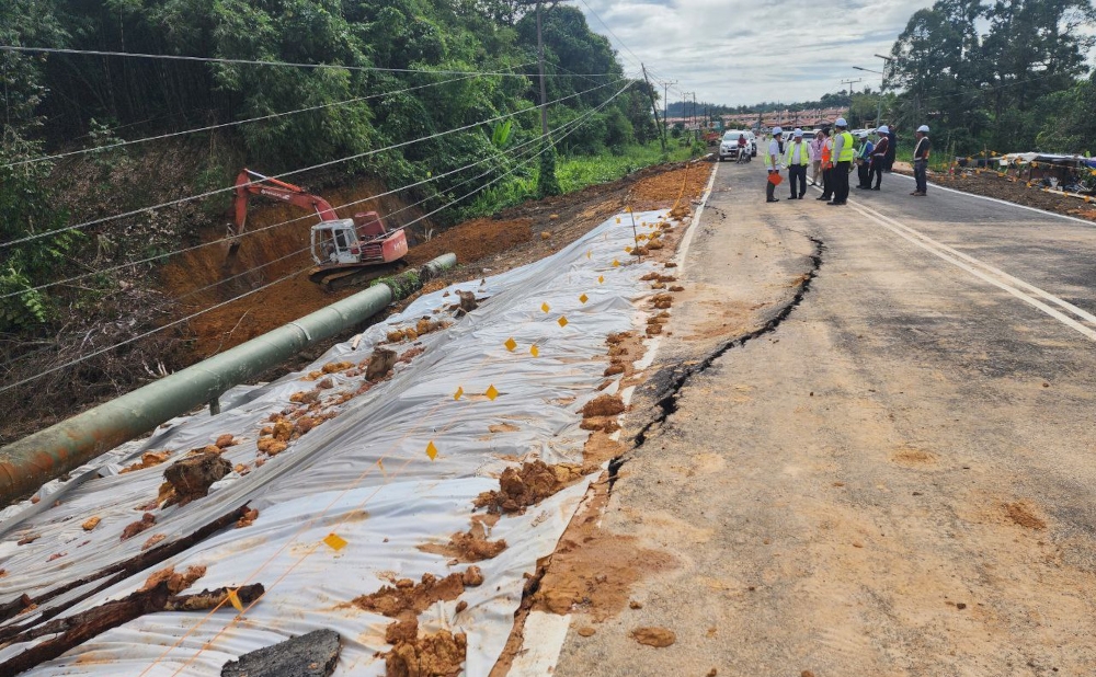 Cracks caused by Saturday’s landslide are seen along a repaired stretch of road. — Borneo Post pic
